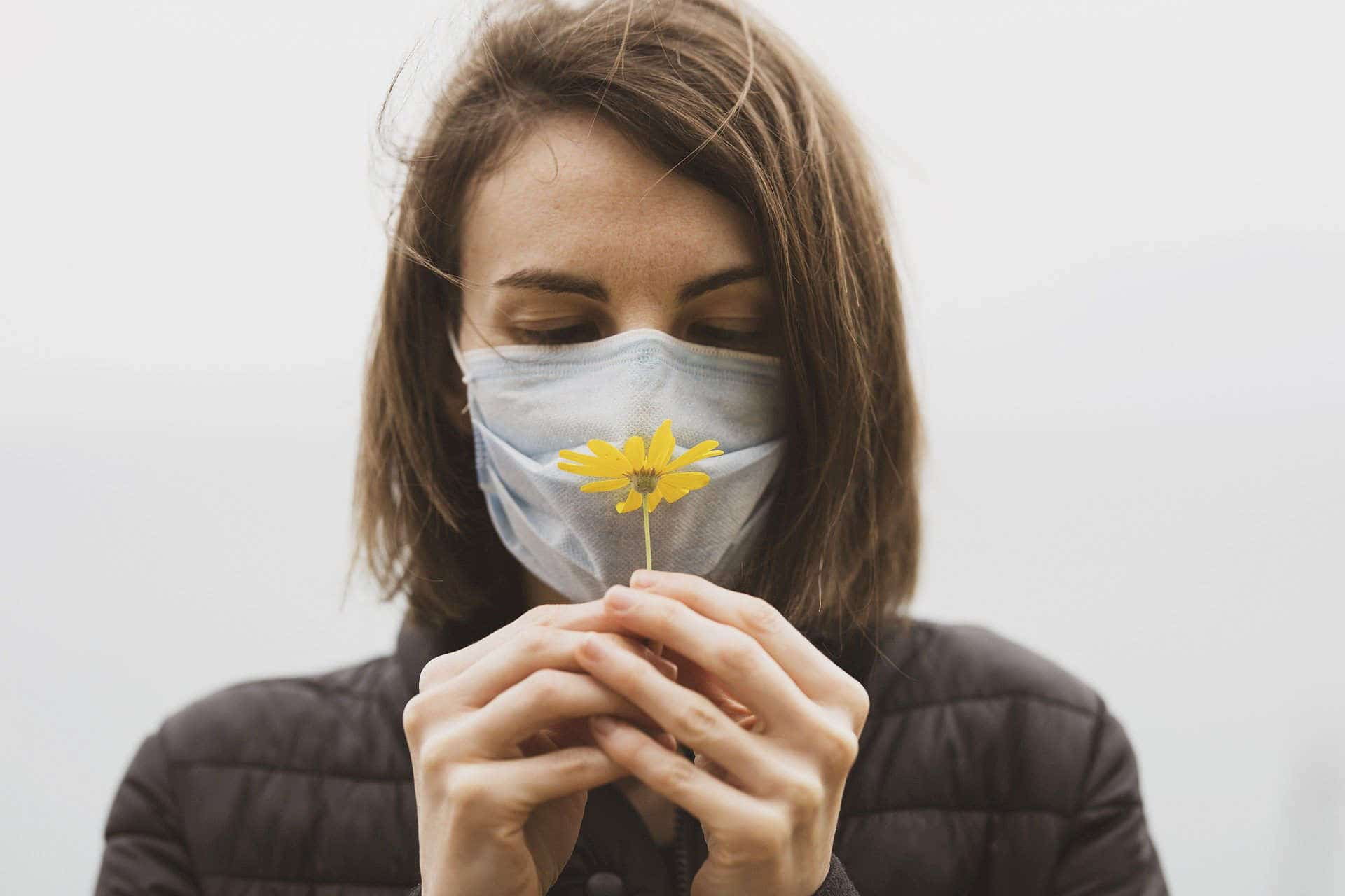 Woman with face mask looking at flower